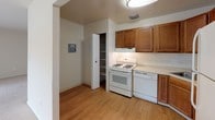 This single-floor residence offers a practical and straightforward layout designed for comfortable everyday living. The kitchen is equipped with warm-toned wood cabinetry providing ample upper and lower storage, light-colored countertops, and a full suite of white appliances including a gas range, dishwasher, and refrigerator. A built-in pantry with open shelving adds additional storage convenience, while durable wood-look flooring ties the space together. An electrical panel is accessible nearby.

The living area is generously sized, featuring neutral carpeting and light-toned walls that create a bright, open atmosphere. A large sliding glass door fitted with vertical blinds allows natural light to fill the room and provides outdoor views, enhancing the overall sense of space.

The bedrooms continue the neutral, carpeted aesthetic and each include closets with built-in rods for organized storage. Windows in the bedrooms allow for additional natural light and outdoor views. The bathroom features a tiled shower surround and a chrome towel bar, maintaining a clean and functional design throughout. Overall, the space presents a cohesive, move-in-ready environment with a calm, neutral palette.