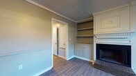 This two-story residence offers 2 bedrooms and 2.5 bathrooms across a well-organized layout connected by a carpeted staircase. The main level centers around a living area distinguished by a wood-burning brick fireplace framed by a detailed white mantel with decorative molding. Flanking the fireplace are built-in shelving units and lower cabinetry, providing generous display and storage space. Crown molding, chair rail detailing, and wood-look flooring contribute a classic character throughout the main level. The kitchen features warm-toned wood cabinetry, light stone-look countertops, a stainless steel sink, and black appliances, with direct access to an exterior door. A half bathroom serves the main level for added convenience. Upstairs, two spacious bedrooms are finished with plush carpet, ceiling fans, and natural light from windows with blinds. One bedroom includes dual closets for ample storage. Each full bathroom is equipped with a tub-shower combination, wood-look tile flooring, and warm wood vanity cabinetry with stone-look countertops. Wall sconces accent the stairwell landing, adding a welcoming ambiance to the transition between floors.