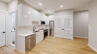Located on Florida Avenue NE in Washington, DC, this one-bedroom, one-bathroom unit offers a efficiently designed layout with contemporary finishes throughout. Light hardwood flooring runs continuously across the living areas and bedroom, creating a cohesive and bright aesthetic.

The kitchen serves as a standout feature, outfitted with floor-to-ceiling white flat-panel cabinetry, marble-style quartz countertops and backsplash, and a full suite of stainless steel appliances including a dishwasher, range, over-the-range microwave, and refrigerator. A matte black single-basin sink adds a modern contrast to the otherwise crisp, white palette. Louvered double doors nearby provide convenient additional storage.

The bedroom is a cozy, well-defined space with neutral gray walls, recessed lighting, and a window that allows natural light and neighborhood views. The room's clean lines and simple layout make it easily adaptable.

The bathroom is finished with large-format gray tile flooring, white vanity cabinetry with a quartz countertop, a framed rectangular mirror with integrated lighting, and matte black fixtures throughout. A full soaking tub completes the space, offering both function and comfort in a polished, modern setting.