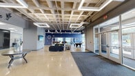 This single-floor space is thoughtfully designed to balance social, recreational, and professional functions within a contemporary, industrial-inspired setting. The expansive lobby welcomes visitors with polished terrazzo-style concrete floors, a coffered ceiling with exposed ductwork, and pendant lighting that creates a refined yet open atmosphere. Seating areas furnished with leather sofas and accent chairs are arranged on geometric-patterned rugs, complemented by a central round display table beneath a bold "Welcome" wall decal.

The open layout transitions seamlessly into a recreational zone featuring a pool table and ping pong table, with large floor-to-ceiling windows and glass doors that invite natural light and provide views of the surrounding greenery. A wet bar area with granite countertops, white cabinetry, and a wall-mounted flat-screen TV adds convenience for gatherings. Nearby, additional lounge seating with warm-toned armchairs offers more intimate social spaces.

A dedicated conference room features carpet tile flooring, a long meeting table, and an expansive window wall overlooking a landscaped exterior, making it ideal for professional meetings. Throughout, bold navy and gray accent walls punctuate the neutral palette, reinforcing a cohesive, modern aesthetic.