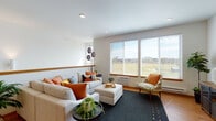 Located at 4185 East Poleline Avenue in Post Falls, Idaho, Unit 205 is a single-floor residence designed with a clean, contemporary aesthetic and a warm, functional layout. The open-concept living and dining area is anchored by warm-toned hardwood-style flooring that flows throughout the main living spaces. Large windows in the living room frame sweeping views of the surrounding landscape, filling the space with abundant natural light and creating an inviting atmosphere. The kitchen is well-appointed with warm wood cabinetry, dark countertops, a tiled backsplash, stainless steel appliances, and a central island with pendant lighting overhead — ideal for both meal preparation and casual dining. A dedicated dining area adjacent to the kitchen offers additional space for entertaining. The bedroom features plush carpeting, generous window coverage with scenic outdoor views, and ample room for furnishings. The full bathroom includes a combined tub and shower, a wood-vanity with a white countertop, and hardwood-style flooring. Recessed lighting throughout the unit adds a polished, modern finish. The overall design balances practicality with comfort, making this Post Falls residence a welcoming and well-equipped home.