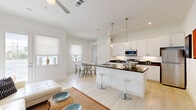 Located at 1001 Frio St in Houston, TX, this modern one-bedroom, one-bathroom residence offers a thoughtfully designed open-concept layout finished with light hardwood flooring and crisp white walls throughout. The combined kitchen, living, and dining area forms the heart of the home, maximizing both function and flow. The kitchen is a standout feature, showcasing dark granite countertops, white shaker cabinetry, stainless steel appliances, and a peninsula island with bar seating beneath elegant pendant lighting. The living area is bright and airy, with a ceiling fan, large windows with roller shades, and a glass door that opens to an outdoor space, filling the room with natural light. A dedicated dining area provides additional space for everyday living. The bedroom is a calm retreat with ample natural light from a window and direct access to the full bathroom. The bathroom mirrors the kitchen's refined aesthetic with matching granite countertops, white cabinetry, a tub-shower combination, and tile flooring. A closet with built-in shelving and hanging rods offers organized storage, and an in-unit stacked washer and dryer add practical convenience to this well-appointed Houston residence.