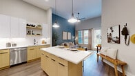 Located in Kissimmee, FL, this thoughtfully designed one-bedroom, one-bathroom residence offers a modern open-concept layout that maximizes every inch of its well-appointed floor plan. Soaring ceilings throughout create a striking sense of volume and airiness, complemented by wood-look flooring that flows seamlessly from room to room.

The combined kitchen, dining, and living area serves as the heart of the home. The contemporary kitchen features two-tone cabinetry — warm wood lower cabinets paired with crisp white upper cabinets — accented by a white subway tile backsplash, under-cabinet lighting, stainless steel appliances, and a central island with bar seating and pendant lighting above. Open shelving adds both function and style. Large windows and a glass patio door flood the living area with natural light and provide direct access to the private patio.

The spacious bedroom is highlighted by a bold teal accent wall, a large window, and impressively tall ceilings, offering a calm and restful retreat. Two closets provide generous storage. The full bathroom is finished with a light wood vanity, white countertop, an illuminated mirror, and a tub-shower combination with tile surround. Additional conveniences include a dedicated laundry area, utility room, and pantry, rounding out this well-equipped residence.