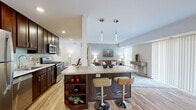 Located at 2701 Keystone Lane in Vienna, Virginia, this single-floor, 2-bedroom, 2-bathroom residence offers a thoughtfully designed layout that maximizes functionality and comfort. The open-concept living area connects the kitchen, dining space, and living room in a seamless flow, creating an inviting and practical environment.

The kitchen is a standout feature, equipped with rich dark-wood cabinetry extending to the ceiling, granite countertops, a subway tile backsplash, and a full suite of stainless steel appliances including a gas range and built-in microwave. A central island with built-in shelving and pendant lighting doubles as a breakfast bar. The adjacent dining area benefits from large sliding glass doors that fill the space with natural light and offer outdoor views. The living room continues this bright, airy feel with oversized windows and neutral carpeting.

The primary bedroom includes a closet and connects to a sleek en-suite bathroom featuring a frameless glass walk-in shower with marble-style tile, dark vanity cabinetry, and a white countertop. The second bedroom is carpeted and serene. The second bathroom offers a tiled tub-shower combination. Wood-look flooring runs throughout the main living areas, tying the space together cohesively.