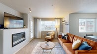 This 2-bedroom, 2-bathroom single-floor residence offers a comfortable and efficiently designed layout across a well-proportioned footprint. The living room serves as the heart of the home, featuring a built-in fireplace, plush carpeting, and a large window that fills the space with natural light and views of the surrounding area. Adjacent to the living room, the dining area is defined by a bold navy accent wall, a second window, and ample room for a full dining set. The kitchen is outfitted with rich wood cabinetry, granite countertops, stainless steel appliances including a full-size refrigerator, and hardwood flooring. A breakfast bar provides additional seating and connects the kitchen to the main living area. A walk-in pantry adds convenient storage. The primary bedroom is a generously sized retreat with carpeted flooring and access to a spacious walk-in closet with wire shelving. The two bathrooms include a tub-shower combination with hardwood flooring. A dedicated laundry room houses a full-size washer and dryer. The hallway features built-in wall shelving, adding both function and character. Textured ceilings are consistent throughout, and the overall design presents a cohesive, modern aesthetic.