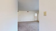 This single-floor, 2-bedroom, 1-bathroom residence offers a functional and well-organized layout across a compact yet efficient floor plan. The living room is a bright, open space featuring plush carpet flooring, a textured ceiling, and a door with a window that allows natural light to filter in, creating an airy atmosphere. Adjacent to the living area, the kitchen is equipped with white cabinetry, light quartz-style countertops, a coil-top electric range, a dishwasher, and light wood-look flooring. A dedicated walk-in pantry closet off the kitchen provides convenient additional storage. The hallway connects the main living spaces to the bedrooms and bathroom, with light flooring that transitions into carpet in the sleeping areas. Both bedrooms feature plush carpet, white walls, and windows fitted with horizontal blinds that bring in natural light. The primary bedroom includes a ceiling fan and a sliding glass door offering outdoor access and exterior views. The second bedroom also enjoys a generous window with outdoor views. The full bathroom features a single-sink vanity with a solid countertop, a large mirror, and a shower/tub combination with a decorative curtain. Three closets throughout the home ensure ample storage. The overall aesthetic is clean, neutral, and move-in ready.