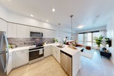 Located in Bellevue, WA, this thoughtfully designed 2-bedroom, 2-bathroom residence offers a bright, modern living experience on a single level. The open-concept layout seamlessly connects the kitchen, dining, and living areas, making excellent use of the available space. Light wood-tone flooring runs throughout, complementing the clean white walls and contemporary finishes.

The kitchen is a standout feature, equipped with stainless steel appliances including a refrigerator, range, microwave, and dishwasher. White flat-panel cabinetry reaches to the ceiling for ample storage, while a textured tile backsplash adds visual interest. A peninsula with seating for four serves as both a prep space and casual dining area, anchored by stylish pendant lighting.

The living room receives generous natural light through large floor-to-ceiling windows that frame views of the surrounding Bellevue cityscape. Both bedrooms offer closet storage and a cozy, well-proportioned layout. The bathrooms feature clean white tile surrounds with tub-shower combinations and modern vanities.

A dedicated laundry area with a stacked Whirlpool washer and dryer adds everyday convenience. With three closets throughout, storage is well-addressed. The residence also includes a welcoming entrance, completing a highly functional and modern floor plan.