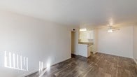 Located at 4730 N 19th Ave in Phoenix, Arizona, this single-floor unit offers a straightforward, functional layout with consistent wood-look flooring throughout. The open-concept living and dining area is bright and welcoming, with neutral white walls that reflect natural light streaming in from the windows. A ceiling fan adds comfort to the living space, which flows seamlessly into the kitchen area.

The kitchen is equipped with white cabinetry, a countertop sink, and standard appliances including a dishwasher and refrigerator. A peninsular breakfast bar separates the kitchen from the living area, providing both a casual dining option and additional counter space. Overhead fluorescent lighting illuminates the kitchen workspace efficiently.

A hallway connects the living area to the private rooms, lined with clean white walls and the same wood-look flooring for visual continuity. The bedrooms are generously proportioned with neutral tones, and at least one features a sliding-door closet offering practical storage. The overall design of the unit is clean and minimal, making it easy to personalize. The consistent use of neutral finishes and durable flooring throughout gives the space a cohesive and well-maintained appearance suited for everyday living in the Phoenix area.