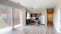 Located at 1250 Ewing St in Fort Wayne, Indiana, this two-bedroom, two-bathroom residence offers a thoughtfully designed single-floor layout that makes efficient use of its space. The open kitchen is a standout feature, showcasing rich dark espresso cabinetry extending to the ceiling, granite countertops, a hexagonal tile backsplash, and a full suite of stainless steel appliances including a refrigerator, range, microwave, and dishwasher. Light wood-style vinyl flooring runs throughout the main living and kitchen areas, complementing the neutral, warm-toned walls. A sliding glass door off the main living area provides access to a private balcony, allowing for natural light and outdoor views of the surrounding brick exterior. Both bedrooms are carpeted and feature generous closet space—one with a sliding-door closet and the other with a dedicated walk-in closet outfitted with built-in shelving and hanging rods. The two bathrooms are well-finished, each featuring dark vanity cabinetry with granite countertops and wood-style flooring. One bathroom includes a tub-shower combination, while the other offers a glass-enclosed walk-in shower. The overall design presents a clean, modern aesthetic with consistent finishes throughout.