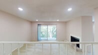 This single-floor residence offers a well-organized layout with a variety of functional spaces throughout. The living area is a standout, featuring a wood-mantled fireplace set on a natural stone hearth, soft neutral carpeting, and a sliding glass door that opens to a private balcony overlooking mature trees, allowing natural light to fill the room. Recessed lighting and a textured ceiling add dimension to the space. Built-in shelving flanks the hallway leading further into the unit, providing convenient storage and display options.

The kitchen is efficiently designed with white cabinetry, granite-look countertops, a gray subway tile backsplash, and wood-look flooring. Stainless steel appliances, including a range, microwave, refrigerator, and dishwasher, complete the space.

The bedrooms are carpeted and feature neutral walls, with natural light provided through windows fitted with blinds. A ceiling fan with a light fixture is present in one bedroom. Each bedroom includes access to a walk-in closet with built-in shelving. The bathroom is equipped with a full soaking tub and shower combination with chrome fixtures and a granite-accented vanity countertop.