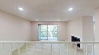 This single-floor residence offers a well-organized layout with a variety of functional spaces throughout. The living area is a standout, featuring a wood-mantled fireplace set on a natural stone hearth, soft neutral carpeting, and a sliding glass door that opens to a private balcony overlooking mature trees, allowing natural light to fill the room. Recessed lighting and a textured ceiling add dimension to the space. Built-in shelving flanks the hallway leading further into the unit, providing convenient storage and display options.

The kitchen is efficiently designed with white cabinetry, granite-look countertops, a gray subway tile backsplash, and wood-look flooring. Stainless steel appliances, including a range, microwave, refrigerator, and dishwasher, complete the space.

The bedrooms are carpeted and feature neutral walls, with natural light provided through windows fitted with blinds. A ceiling fan with a light fixture is present in one bedroom. Each bedroom includes access to a walk-in closet with built-in shelving. The bathroom is equipped with a full soaking tub and shower combination with chrome fixtures and a granite-accented vanity countertop.