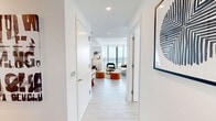 Located in the heart of downtown Miami, this thoughtfully designed 3-bedroom, 2-bathroom residence offers a sophisticated urban living experience across a single, well-appointed floor. Light-toned tile flooring runs throughout, complementing the clean, contemporary aesthetic defined by crisp white walls and recessed lighting.

A welcoming hallway with curated wall art leads into the expansive open-concept kitchen and living area, bathed in natural light from dramatic floor-to-ceiling glass windows that frame panoramic views of the Miami skyline and Biscayne Bay. The sleek, galley-style kitchen features stainless steel appliances, white cabinetry extending to the ceiling, a striking marble-topped island with pendant lighting, and generous counter space. The adjacent living room is bright and airy, with sliding glass doors opening to the outdoors, creating a seamless indoor-outdoor flow.

The spacious primary bedroom enjoys its own floor-to-ceiling windows with direct balcony access and sweeping views, offering a serene retreat. Two additional bedrooms are equally well-lit with large windows overlooking the city. Both bathrooms are finished in glossy white tile with frameless glass-enclosed showers and minimalist fixtures. Two closets provide practical storage throughout. The overall ambiance is modern, light-filled, and polished.