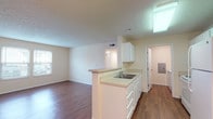 Located at 815 Cole Dr in Johnstown, Ohio, this single-floor unit offers a functional and well-organized layout designed for comfortable everyday living. The open-concept kitchen serves as the heart of the home, featuring white cabinetry, light countertops, a double-basin sink, and a peninsula that connects seamlessly to the living area. White appliances, including a refrigerator and range, are neatly integrated into the kitchen's galley-style design, while a skylight-style ceiling fixture provides bright overhead illumination. Warm wood-style flooring flows throughout the main living areas and hallway, lending a cohesive and inviting feel to the space. A dedicated hallway connects the various rooms with ease, providing a clean and organized transition between areas. The bedrooms are finished with plush neutral carpeting, creating a comfortable and quiet retreat. The bathroom is well-appointed with a single-sink vanity, a large mirror with overhead lighting, and a full tub-shower combination with clean white surrounds. A dedicated in-unit laundry area accommodates a full-sized washer and dryer with overhead wire shelving for additional storage. Textured ceilings and neutral wall tones throughout contribute to the unit's bright, clean aesthetic.