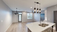 This well-appointed single-story home in North Little Rock, AR offers a thoughtfully designed layout with two bedrooms and two full bathrooms. The open-concept living and dining area is anchored by light hardwood-style flooring, neutral gray walls, and an eye-catching modern chandelier. A ceiling fan and multiple windows allow natural light to fill the space, with a glass door providing outdoor access and views of the surrounding neighborhood. The kitchen is outfitted with white shaker-style cabinetry, quartz countertops, stainless steel appliances including a French door refrigerator and range, and stylish pendant lighting over the island with a deep double sink. The primary bedroom is a comfortable retreat with its own ceiling fan and direct access to a luxurious en-suite bathroom featuring marble-look tile flooring, a glass-enclosed walk-in shower with a rainfall showerhead, and a white vanity with quartz countertop. A well-organized walk-in closet with built-in shelving adjoins the suite. The second bathroom offers a tub-shower combo with glass sliding doors, marble-look tile, and matching vanity finishes. The second bedroom features the same wood-style flooring and a ceiling fan. Each bedroom includes a dedicated closet, completing a functional and modern floor plan.