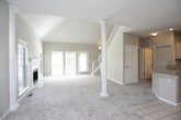 This two-story home is designed with an open and airy layout that makes a strong first impression. The main living area showcases dramatic vaulted ceilings supported by decorative white columns, creating a grand sense of vertical space. A white-mantled fireplace with tile surround serves as the room's focal point, flanked by windows that invite natural light and views of surrounding greenery. Neutral-toned carpet and warm beige walls run throughout the living spaces, establishing a cohesive and calm aesthetic.

The kitchen is well-appointed with light wood cabinetry, granite countertops, stainless steel appliances, and a peninsula with an integrated sink — ideal for both everyday use and casual dining. Tile flooring transitions seamlessly between the kitchen and adjacent areas. A staircase with a white balustrade connects to the upper level, where generously sized bedrooms feature vaulted ceilings, ceiling fans, skylights, and large closets. The bathrooms are finished with granite vanity tops, light wood cabinetry, built-in shelving, and a tub-shower combination. A dedicated laundry closet with full-size washer and dryer adds everyday convenience.