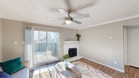 This thoughtfully designed single-floor residence offers a comfortable and functional layout across five distinct spaces. The combined kitchen and living room serves as the heart of the home, highlighted by a striking white stone corner fireplace with a classic mantel and a ceiling fan with integrated lighting. Wood-look flooring runs throughout the living area, which opens directly to a private balcony through sliding glass doors, allowing abundant natural light to fill the room. Crown molding and a textured ceiling add architectural character throughout.

The kitchen is efficiently laid out with white shaker-style cabinetry, dark hardware, a hexagonal tile backsplash, light stone countertops, and a full suite of stainless steel appliances. A breakfast bar provides a casual dining option adjacent to the kitchen.

The bedroom offers a comfortable retreat with plush wall-to-wall carpeting, a ceiling fan, a natural light source from a window, and access to a dedicated closet. The neutral color palette creates a calm and restful atmosphere.

The full bathroom features a tiled tub and shower combination, a white vanity with countertop, and wood-look flooring that ties cohesively to the rest of the unit. A hallway connects the rooms, completing this efficient and well-finished floor plan.