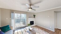 This thoughtfully designed single-floor residence offers a comfortable and functional layout across five distinct spaces. The combined kitchen and living room serves as the heart of the home, highlighted by a striking white stone corner fireplace with a classic mantel and a ceiling fan with integrated lighting. Wood-look flooring runs throughout the living area, which opens directly to a private balcony through sliding glass doors, allowing abundant natural light to fill the room. Crown molding and a textured ceiling add architectural character throughout.

The kitchen is efficiently laid out with white shaker-style cabinetry, dark hardware, a hexagonal tile backsplash, light stone countertops, and a full suite of stainless steel appliances. A breakfast bar provides a casual dining option adjacent to the kitchen.

The bedroom offers a comfortable retreat with plush wall-to-wall carpeting, a ceiling fan, a natural light source from a window, and access to a dedicated closet. The neutral color palette creates a calm and restful atmosphere.

The full bathroom features a tiled tub and shower combination, a white vanity with countertop, and wood-look flooring that ties cohesively to the rest of the unit. A hallway connects the rooms, completing this efficient and well-finished floor plan.