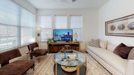 This single-floor residence offers a thoughtfully designed layout that balances functionality with contemporary style. The kitchen is a standout feature, showcasing white flat-panel cabinetry extending to the ceiling, a textured gray tile backsplash, stainless steel appliances including a refrigerator, range, microwave, and dishwasher, and a white quartz countertop island with seating for casual dining. Light wood-tone flooring grounds the space with warmth.

The living area is bright and welcoming, with multiple windows fitted with horizontal blinds that allow generous natural light. A glass-top coffee table and neutral furnishings contribute to the relaxed, modern atmosphere. A glazed entry door with transom window further enhances the sense of openness.

The bedrooms feature plush carpeting, ceiling fans, and windows with views of the surrounding exterior. Each room offers a calm, neutral palette with ample space for furnishings. At least one bedroom includes a walk-in closet.

The bathrooms are clean and functional, with white tilework, undermount sinks, white cabinetry with brushed gold hardware, and a tub-shower combination. Tile flooring completes the polished, cohesive look throughout the home.