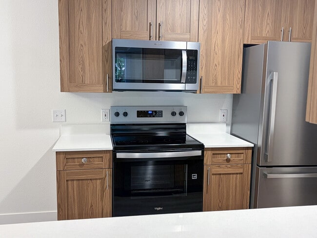 Modern stainless steel appliances paired with warm cabinetry create a kitchen you'll love coming home to. - Pinebrook
