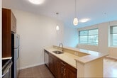 Located at 100 Newkirk Street in Jersey City, NJ, this one-bedroom, one-bathroom residence offers a well-designed layout that maximizes its efficient footprint across a single floor. The open-concept kitchen and living area form the heart of the home, where warm hardwood flooring extends throughout the living spaces. The kitchen is outfitted with rich dark wood cabinetry, light stone countertops, stainless steel appliances including a refrigerator and range, a built-in dishwasher, and a peninsula with pendant lighting overhead — a functional and stylish centerpiece. Multiple windows in the living area invite generous natural light and offer views of the surrounding Jersey City neighborhood. The bedroom is a comfortable, well-proportioned retreat featuring the same hardwood floors, large windows with city views, and a closet with built-in shelving for ample storage. A second closet option is also present. The bathroom is clean and well-appointed, featuring a full soaking tub with mosaic tile surround in soft teal and white tones, white cabinetry, and a vanity mirror. The overall aesthetic throughout the space is modern and neutral, with white walls and clean finishes that create a bright, airy ambiance throughout.