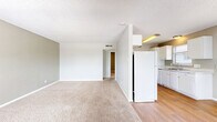 Located at 845 S Business IH-35 in New Braunfels, Texas, this one-bedroom, one-bathroom unit offers a functional and well-organized single-floor layout. The galley-style kitchen is a standout feature, finished with warm hardwood-style flooring, white cabinetry, light stone countertops, and white appliances including an electric range and refrigerator. A stainless steel sink with a window above provides natural light to the cooking space, while ample upper and lower cabinet storage ensures practicality.

The spacious bedroom is finished with plush wall-to-wall carpeting and neutral gray walls, creating a calm and comfortable retreat. A ceiling fan with integrated lighting adds both function and comfort. The room features multiple doors, including access to a closet, providing useful storage options.

The full bathroom is finished with hardwood-style flooring and includes a white vanity with a speckled countertop, a mirrored medicine cabinet, and a clean white tub-shower combination with tiled surround. Throughout the unit, a consistent neutral color palette of soft grays and whites creates a cohesive, clean aesthetic. A dedicated entrance and hallway complete the layout, providing a smooth and connected flow between all living spaces.
