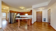 Located at 311 Bunting Ln in Mankato, Minnesota, this single-floor, 3-bedroom, 1-bathroom unit offers a well-organized layout designed for comfortable everyday living. The open-concept kitchen serves as the heart of the space, featuring warm oak cabinetry, granite countertops, stainless steel appliances including a refrigerator, range, and dishwasher, and a curved peninsula that provides additional prep space and a natural divide between the kitchen and living area. Hardwood-style flooring flows throughout the main living and kitchen areas, adding warmth and continuity. The living area is bright and inviting, with a window that brings in natural light. The three bedrooms are carpeted for comfort, each offering closet storage and windows with blinds. Six-panel wood doors are a consistent design detail throughout the unit, adding a classic touch. The bathroom is clean and functional, appointed with a granite-top vanity with wood cabinetry, a tub/shower combination with a grab bar, and hardwood-style flooring. The neutral color palette and consistent finishes throughout create a cohesive and livable atmosphere well-suited for a variety of occupants.