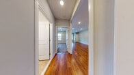 Located at 289 Ridge Road in Wethersfield, Connecticut, this single-floor unit offers a well-designed layout with modern finishes throughout. The open-concept living and kitchen area serves as the central hub of the space, featuring warm hardwood flooring that extends through the main living areas and recessed lighting overhead. Neutral gray walls provide a clean, contemporary backdrop throughout.

The kitchen is equipped with white shaker-style cabinetry, granite countertops, and a mosaic tile backsplash. Stainless steel appliances include a gas range, over-the-range microwave, and refrigerator. A peninsula with a granite countertop and decorative pendant lighting connects the kitchen to the living area, making it well-suited for both casual dining and entertaining.

The bedroom features plush carpeting, a large window with an outdoor view, and recessed lighting, creating a comfortable and naturally lit retreat. The bathroom includes a vanity with a dark wood cabinet and white countertop, a full tub and shower combination, and stone-look tile flooring.

A dedicated laundry area houses a stacked front-loading washer and dryer, adding everyday convenience. The hallway connects all areas efficiently, with clean white trim and tile flooring at the entry. Overall, the unit presents a cohesive, move-in-ready aesthetic with thoughtful modern updates.