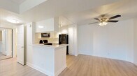 Located on Burbank Boulevard in the Van Nuys neighborhood of Los Angeles, this 3-bedroom, 2-bathroom residence offers a well-organized single-floor layout designed for comfortable everyday living. The open-concept living and kitchen area forms the heart of the home, featuring light hardwood-style flooring, a ceiling fan, and a seamless flow between spaces. The kitchen is outfitted with crisp white cabinetry extending to the ceiling for ample storage, a peninsula with a light stone countertop, a stainless steel sink, and black appliances including a range, built-in microwave, and refrigerator. Track lighting illuminates the workspace efficiently. The living area opens directly to a private balcony through a sliding glass door, offering pleasant views of surrounding greenery and natural light. The three bedrooms are carpeted and feature mirrored sliding closet doors and windows that bring in natural light. The spacious primary bedroom provides a generously sized layout. Both bathrooms are finished with white vanities, light wood-style flooring, and tub-shower combinations. A hallway connects the bedrooms and bathrooms, providing a practical and organized flow throughout the residence. The overall aesthetic is clean, bright, and neutral throughout.