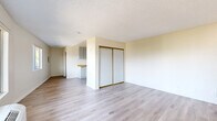 Located at 249 W Alameda Ave in Burbank, California, this studio unit offers a practical and efficient single-floor layout. The open living area is finished with light wood-style vinyl plank flooring that runs throughout, lending a clean and modern aesthetic to the space. Warm neutral tones on the walls, paired with a textured ceiling, create a bright and inviting ambiance. A large sliding window near the entry door allows generous natural light to pour in while framing pleasant views of the surrounding neighborhood and distant mountains. A wall-mounted HVAC unit provides climate control directly within the living area. Built-in sliding closet doors offer convenient storage within the main room. The kitchenette, visible from the living area, features gray cabinetry, a butcher block-style countertop, and an L-shaped layout that maximizes functionality within a compact footprint. The full bathroom is finished in a clean, all-white palette, complete with a vanity featuring an integrated sink, a toilet, and a tub-shower combination with tiled surround. Wood-style flooring continues into the bathroom, maintaining a cohesive look throughout the unit. This space is well-suited for those seeking a low-maintenance, efficiently designed home in a convenient Burbank location.
