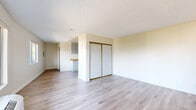 Located at 249 W Alameda Ave in Burbank, California, this studio unit offers a practical and efficient single-floor layout. The open living area is finished with light wood-style vinyl plank flooring that runs throughout, lending a clean and modern aesthetic to the space. Warm neutral tones on the walls, paired with a textured ceiling, create a bright and inviting ambiance. A large sliding window near the entry door allows generous natural light to pour in while framing pleasant views of the surrounding neighborhood and distant mountains. A wall-mounted HVAC unit provides climate control directly within the living area. Built-in sliding closet doors offer convenient storage within the main room. The kitchenette, visible from the living area, features gray cabinetry, a butcher block-style countertop, and an L-shaped layout that maximizes functionality within a compact footprint. The full bathroom is finished in a clean, all-white palette, complete with a vanity featuring an integrated sink, a toilet, and a tub-shower combination with tiled surround. Wood-style flooring continues into the bathroom, maintaining a cohesive look throughout the unit. This space is well-suited for those seeking a low-maintenance, efficiently designed home in a convenient Burbank location.