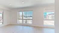 Located in the vibrant heart of Denver, CO, this modern studio offers a thoughtfully designed open-concept layout that maximizes every square foot. Light ash hardwood flooring flows throughout the space, complementing the clean white walls and recessed lighting that create a bright, airy atmosphere.

The well-appointed kitchen is a standout feature, showcasing a sleek combination of navy lower cabinetry and warm wood upper cabinets. Stainless steel appliances — including a full-size refrigerator, range, dishwasher, and built-in microwave — line the galley-style setup, anchored by a crisp white countertop and modern black fixtures.

Large picture windows dominate the living area, flooding the space with natural light while framing impressive panoramic views of the Denver skyline and surrounding cityscape. The expansive glazing offers dynamic sightlines of neighboring high-rises and urban architecture, providing a true connection to the energy of downtown.

The bathroom is efficiently designed with a full tub-shower combo featuring floor-to-ceiling white tile, a wood-accented vanity with white countertop, matte black hardware, and a stacked in-unit washer and dryer. A hallway and closet complete the layout, offering practical storage solutions. This studio delivers a polished, contemporary urban living experience in one of Denver's most sought-after locations.