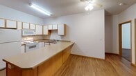 Located at 24 Eighth St N in Fargo, North Dakota, this single-floor unit offers a functional and well-organized layout designed for comfortable everyday living. The open-concept kitchen and living area form the heart of the space, featuring warm wood-toned laminate flooring and a peninsula counter with a breakfast bar that seamlessly connects the kitchen to the living area. The kitchen is equipped with white appliances — including a refrigerator, electric range, built-in microwave, and dishwasher — complemented by white cabinetry with oak-trimmed accents, ample counter space, and a stainless sink. A ceiling fan overhead adds to the practical comfort of the shared living space. The living area is generously proportioned, offering flexibility for various furniture arrangements, with doorways leading to the private bedrooms. The bedrooms feature plush carpeting and bi-fold closet doors providing accessible storage. Two bathrooms serve the unit: one features a full soaking tub and shower combo with a vanity and tile flooring, while the second offers a standalone shower stall with open wire shelving for additional storage. Consistent wood-tone trim and baseboards tie the interior together, creating a cohesive and clean aesthetic throughout the entire space.