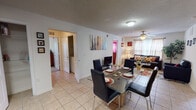 This single-floor residence offers a functional and comfortable layout designed for everyday living. The entryway welcomes you with light tile flooring that continues throughout the main living areas, setting a clean and cohesive tone. The open-plan dining and living area provides generous space for both relaxing and entertaining. The dining area accommodates a glass-top table with seating for four, while the living room features a ceiling fan, large area rug, and windows that allow natural light to fill the space. The kitchen is efficiently laid out with warm wood cabinetry, granite-style countertops, black appliances including a refrigerator, electric range, and built-in microwave, plus a convenient walk-in pantry for additional storage. Two well-sized bedrooms offer carpeted or tiled flooring, windows with curtains, and room for standard bedroom furnishings. Each bedroom is served by its own bathroom, both featuring tub-shower combinations and tile flooring. A dedicated in-unit laundry closet with a full-size washer and dryer adds a practical convenience. Overall, the residence presents a bright, livable environment with a straightforward, efficient floor plan.