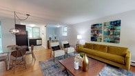Located in the Chestnut Hill neighborhood of Philadelphia, this single-floor residence at 7715 McCallum St offers a thoughtfully designed open-concept layout that maximizes both space and functionality. The living area is a welcoming focal point, characterized by warm hardwood flooring, soft neutral walls, and abundant natural light streaming in through multiple windows. The open floor plan seamlessly connects the living room to the kitchen and dining areas, creating an ideal environment for both relaxed everyday living and entertaining guests. The kitchen is outfitted with dark cabinetry and appliances, offering a stylish contrast to the lighter tones throughout the rest of the space. A dining area with ample room for seating is visible adjacent to the kitchen, making mealtime gatherings convenient and comfortable. Throughout the home, the clean lines and understated design allow the architecture to speak for itself, while carefully considered details add warmth and character. The consistent hardwood flooring ties the interconnected spaces together, enhancing the sense of flow and cohesion. With its bright interiors, open layout, and practical design, this Philadelphia residence presents a comfortable and inviting living environment.