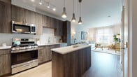 Located at 200 Market St in Montvale, NJ, this single-floor residence offers a thoughtfully designed open-concept layout with contemporary finishes throughout. The kitchen serves as a central highlight, featuring rich dark wood cabinetry, stainless steel appliances including a gas range, microwave, refrigerator, and dishwasher, complemented by a white subway tile backsplash and a sleek center island with a light quartz countertop. Pendant lighting and track lighting illuminate the space, which flows seamlessly into the living and dining areas. The living room is bright and inviting, benefiting from large windows that allow generous natural light and views of the surrounding community. Light wood-tone flooring extends throughout the main living spaces, enhancing the open, airy feel. A dedicated dining nook sits adjacent to the living area, offering an intimate space for meals. The bedroom is a serene retreat, dressed in soft blue accent tones with large windows, ample natural light, and hardwood flooring. The bathroom is elegantly finished with marble-look tile on both the floors and walls, a soaking tub with a shower, and a wood-toned vanity with a white countertop and a wide mirror. A stacked in-unit washer and dryer adds everyday convenience to this well-appointed home.