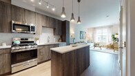 Located at 200 Market St in Montvale, NJ, this single-floor residence offers a thoughtfully designed open-concept layout with contemporary finishes throughout. The kitchen serves as a central highlight, featuring rich dark wood cabinetry, stainless steel appliances including a gas range, microwave, refrigerator, and dishwasher, complemented by a white subway tile backsplash and a sleek center island with a light quartz countertop. Pendant lighting and track lighting illuminate the space, which flows seamlessly into the living and dining areas. The living room is bright and inviting, benefiting from large windows that allow generous natural light and views of the surrounding community. Light wood-tone flooring extends throughout the main living spaces, enhancing the open, airy feel. A dedicated dining nook sits adjacent to the living area, offering an intimate space for meals. The bedroom is a serene retreat, dressed in soft blue accent tones with large windows, ample natural light, and hardwood flooring. The bathroom is elegantly finished with marble-look tile on both the floors and walls, a soaking tub with a shower, and a wood-toned vanity with a white countertop and a wide mirror. A stacked in-unit washer and dryer adds everyday convenience to this well-appointed home.