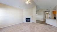 Located at 59 Maryturner Ct in Newnan, Georgia, this well-appointed single-story home offers three bedrooms and two bathrooms across a comfortable and thoughtfully laid-out floor plan. The living room serves as the heart of the home, showcasing soaring vaulted ceilings, a ceiling fan, soft carpeting, and a marble-surround fireplace as a focal point. Large windows flood the space with natural light, creating a bright and welcoming atmosphere. The kitchen features warm wood cabinetry, granite countertops, stainless steel appliances, and a peninsula with a sink — seamlessly connecting to the living and dining areas over hardwood-style flooring. A walk-in pantry closet adds practical storage. The generously sized primary bedroom continues the vaulted ceiling design with its own ceiling fan and direct access to a private bathroom, which includes a soaking tub, granite vanity, and wood-style flooring. Additional bedrooms are carpeted and include closets, offering versatile space for guests or a home office. The attached garage features a clean epoxy-coated floor and a paneled door with windows. Throughout, the home maintains a neutral, cohesive palette that lends itself to a calm and livable environment.