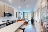 Located at 501 North Christopher Columbus Boulevard in Philadelphia, this thoughtfully designed one-bedroom, one-bathroom unit offers a smart and modern living experience. The open-concept layout seamlessly connects the kitchen and living room, maximizing the efficient use of space. The kitchen is outfitted with two-tone cabinetry — light wood uppers and charcoal gray lowers — complemented by white quartz countertops, a subway tile backsplash, and a full suite of stainless steel appliances including a refrigerator, range, microwave, and dishwasher. A movable kitchen island with bar seating adds flexible dining and prep space. Light wood-style flooring flows throughout the main living areas, lending a warm, contemporary feel. The living room is anchored by large windows that invite natural light and provide outdoor views, creating an airy atmosphere. A private patio extends the living space outdoors. The bedroom features plush carpet, large windows with outdoor views, and a dedicated closet with built-in shelving. The bathroom is finished with a gray vanity, wood-look flooring, and a tub-shower combination. Recessed lighting throughout and clean white walls give the entire unit a bright, modern ambiance.