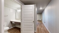 Located at 1525 W Havens Ave in Mitchell, South Dakota, this 2-bedroom, 1-bathroom unit offers a practical and well-appointed single-floor layout. The kitchen serves as a central highlight, featuring a peninsula with granite-style countertops, taupe cabinetry, stainless steel refrigerator and range, and a built-in microwave — all set atop warm-toned luxury vinyl plank flooring that extends through the main living areas. The open arrangement connects the kitchen to the living area, creating a cohesive and functional space. The primary bedroom is generously sized and finished with soft carpet flooring, neutral gray walls, and a large window that brings in natural light. The second bedroom mirrors this comfortable feel, also offering carpeted floors and a closet. Both bedrooms are served by raised-panel white doors. The full bathroom is clean and efficiently designed, featuring a combination tub-shower, a wood-toned vanity with an undermount sink, a large mirror, and vinyl plank flooring. A hallway connects the living space to the bedrooms and bath, providing a smooth, logical flow throughout. The unit's neutral color palette and updated finishes offer a move-in-ready living environment.