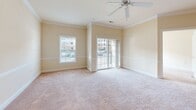 Located at 1300 Deemers Landing in New Castle, Delaware, this well-appointed 2-bedroom, 1-bathroom residence offers a functional and comfortable layout across a single floor. The open-concept living and kitchen area serves as the heart of the home, where warm-toned tile flooring transitions seamlessly into plush wall-to-wall carpeting in the living room. The kitchen is outfitted with light wood cabinetry reaching toward the ceiling, granite-style countertops, and stainless steel appliances including a range, microwave, and refrigerator. A peninsula island with decorative columns provides additional prep space and separates the kitchen from the living area. Crown molding adds a refined architectural detail throughout the main living spaces, which are brightened by recessed lighting and a ceiling fan. Sliding glass doors open to a private balcony overlooking the community. Both bedrooms are carpeted and filled with natural light from large windows, with the primary bedroom offering generous proportions and a closet. The second bedroom also features a ceiling fan and ample natural light. The full bathroom includes a tiled tub-shower combo, a vanity with wood cabinetry, and tile flooring. A dedicated closet provides additional storage within the unit.