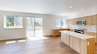 Located at 23905 Van Ry Blvd in Mountlake Terrace, WA, this two-bedroom, two-bathroom residence offers a well-designed single-floor layout with a clean, modern aesthetic throughout. The open-concept living and kitchen area serves as the heart of the home, featuring warm wood-toned cabinetry, white quartz countertops, a kitchen island, and stainless steel appliances. Large sliding glass doors flood the space with natural light and open to an outdoor patio, while additional windows frame views of lush, mature greenery. Hardwood-style flooring runs throughout the main living areas, lending warmth and continuity.

The primary bedroom is generously sized, with hardwood-style floors, dual windows overlooking the treetops, and a spacious closet. The second bedroom features soft carpeting, a ceiling fan, a window with verdant views, and its own closet. Both bedrooms provide a comfortable and well-lit retreat.

The two bathrooms are thoughtfully appointed. One includes a full tub-shower combo with chrome fixtures, while the other features a walk-in shower, wood-toned vanity cabinetry, and hardwood-style flooring. A connecting hallway ties all rooms together efficiently. Throughout, the residence maintains a bright, neutral palette that creates a calm and cohesive atmosphere.