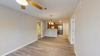 Located at 6306 Old Mooretown Rd in Williamsburg, VA, this single-floor residence offers a functional and well-appointed 2-bedroom, 2-bathroom layout. The open-concept living and dining area is anchored by durable hardwood-style flooring and a ceiling fan with pendant lighting, creating a bright and airy atmosphere. Natural light filters in through a large front-facing window, enhancing the clean, neutral color palette throughout.

The kitchen features dark espresso cabinetry, granite-style countertops, stainless steel appliances including a side-by-side refrigerator and electric range, a double-basin sink, and a breakfast bar peninsula that seamlessly connects to the living area. Recessed lighting adds a polished touch to the cooking space.

Both bedrooms are comfortably sized, each equipped with a ceiling fan and windows offering natural light. The primary bedroom is generously proportioned and finished with plush carpeting, while the second bedroom features the same hardwood-style flooring found in the main living areas. Each bedroom is supported by a dedicated closet for storage convenience.

The bathrooms are tastefully finished, with one featuring a modern floating vanity, granite-style countertop, and contemporary light fixture. A hallway connects the bedrooms to the shared living spaces, contributing to an efficient and cohesive floor plan throughout this Williamsburg home.