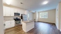 Located at 1 Glover Ave in Norwalk, CT, this well-designed 2-bedroom, 2-bathroom residence offers a thoughtful single-floor layout with a clean, contemporary aesthetic throughout. The open-concept kitchen and living area serves as the heart of the home, showcasing white shaker cabinetry, granite countertops, a central island, and a full suite of stainless steel appliances, including a gas range, microwave, dishwasher, and refrigerator. Rich hardwood-style flooring flows through the main living areas, adding warmth and continuity to the space. Both bedrooms are comfortably sized, featuring plush wall-to-wall carpeting and large windows fitted with blinds that frame lush, green tree views, filling each room with natural light. The primary bedroom offers a generous footprint ideal for a full furniture arrangement. Each of the two bathrooms is finished with large-format tile flooring, white vanity cabinetry with brushed nickel hardware, white quartz countertops, and broad mirrors. One bathroom includes accessibility-friendly grab bars. A dedicated closet provides additional storage. The overall ambiance is bright, neutral, and move-in ready, with a consistent modern finish palette carried throughout the entire residence.