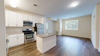 Located at 1 Glover Ave in Norwalk, CT, this well-designed 2-bedroom, 2-bathroom residence offers a thoughtful single-floor layout with a clean, contemporary aesthetic throughout. The open-concept kitchen and living area serves as the heart of the home, showcasing white shaker cabinetry, granite countertops, a central island, and a full suite of stainless steel appliances, including a gas range, microwave, dishwasher, and refrigerator. Rich hardwood-style flooring flows through the main living areas, adding warmth and continuity to the space. Both bedrooms are comfortably sized, featuring plush wall-to-wall carpeting and large windows fitted with blinds that frame lush, green tree views, filling each room with natural light. The primary bedroom offers a generous footprint ideal for a full furniture arrangement. Each of the two bathrooms is finished with large-format tile flooring, white vanity cabinetry with brushed nickel hardware, white quartz countertops, and broad mirrors. One bathroom includes accessibility-friendly grab bars. A dedicated closet provides additional storage. The overall ambiance is bright, neutral, and move-in ready, with a consistent modern finish palette carried throughout the entire residence.