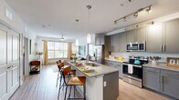 Located at 100 District Dr in Asheville, NC, this thoughtfully designed 2-bedroom, 2-bathroom residence offers a comfortable and functional single-floor layout. The open-concept kitchen and living area serves as the heart of the home, featuring grey cabinetry, granite countertops, a large center island with bar seating, pendant lighting, track lighting, and a full suite of stainless steel appliances with a classic white subway tile backsplash. Wood-look flooring flows throughout the main living areas, complementing the bright, airy aesthetic. The living room benefits from large windows that invite abundant natural light and outdoor views, and is equipped with a ceiling fan for added comfort. Both bedrooms are carpeted and well-sized, each with ceiling fans and windows offering exterior views. The primary bedroom includes access to a closet and a private bathroom featuring a glass-enclosed shower, granite vanity, and grey cabinetry. The second bathroom offers a shower/tub combination and matching finishes. Five closets provide generous storage throughout. An in-unit laundry area adds everyday convenience. The residence presents a clean, modern aesthetic with a neutral color palette throughout.