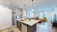 This thoughtfully designed one-bedroom, two-bathroom residence in Billings, Montana offers a contemporary open-concept floor plan that maximizes every square foot. Light wood-tone flooring flows throughout the main living areas, creating a warm and cohesive aesthetic.

The kitchen is a standout feature, anchored by a large center island with a striking navy-blue base and crisp white quartz countertop — ideal for both meal prep and casual dining with bar seating. Gray shaker-style cabinetry, a subway tile backsplash, stainless steel appliances, and pendant lighting complete the well-appointed space.

The kitchen opens seamlessly into the living room, which is bathed in natural light from expansive windows and a sliding glass door leading to a private balcony. The bright, airy living space provides a comfortable and inviting atmosphere.

The primary bedroom features plush carpeting, a dedicated window for natural light, and direct access to a full en-suite bathroom. The bathroom offers dual vanities with ample cabinetry, wood-look flooring, and a walk-in closet with built-in shelving for generous storage. A second full bathroom provides added convenience for guests. The clean, neutral palette and modern finishes throughout give the entire residence a polished, move-in-ready appeal.