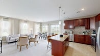 Located at 1 Garden Park Blvd in Cherry Hill, NJ, this well-appointed 2-bedroom, 2-bathroom single-floor residence offers a thoughtfully designed open-concept layout. The kitchen is a standout feature, showcasing rich cherry wood cabinetry, granite countertops, a mosaic tile backsplash, stainless steel appliances, and a center island with bar seating — all finished with light tile flooring. The kitchen flows seamlessly into the dining area and living room, where large windows and sliding glass doors flood the space with natural light and provide direct access to a private balcony overlooking lush green surroundings. The spacious primary bedroom features plush carpeting, multiple windows with outdoor views, and a generous walk-in closet with built-in wire shelving. The bathrooms are well-finished with granite vanities, cherry wood cabinetry, and tile flooring; the primary bath includes a glass-enclosed walk-in shower with tile surround. A dedicated laundry room with in-unit washer and dryer adds everyday convenience. With three closets, a pantry, and a hallway connecting all areas, this residence delivers both comfort and functionality throughout its well-utilized floor plan.
