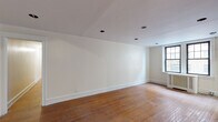 Located at 5515 Wissahickon Ave in Philadelphia's 19144 zip code, this single-floor unit offers a thoughtfully laid-out living space defined by warm hardwood flooring that runs throughout the main living and bedroom areas. The open living spaces are bright and neutrally finished with crisp white walls, recessed lighting, and clean white baseboard trim that lends a classic, timeless character to the interior.

The main living area is generously proportioned, featuring multiple recessed lights and large multi-pane windows that invite natural light into the room. Elegant French doors with dark wood frames provide a distinguished entry point, adding architectural charm to the space. A second open living or flex room mirrors the same neutral palette and hardwood floors, enhanced by additional recessed lighting.

The galley-style kitchen is well-equipped with warm oak cabinetry, ample counter space, a white gas range, refrigerator, and a stainless steel sink. Tile flooring and recessed lighting complete the functional layout.

The bedroom is a comfortable, well-proportioned room featuring a ceiling fan, rich dark wood doors with closet storage, and the same warm hardwood flooring found throughout. The bathroom is cleanly finished with white subway tile wainscoting, large-format floor tile, a vanity with mirror, and a natural light-admitting window.