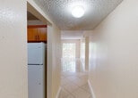 Located at 11105 SW 200 St in Cutler Bay, Florida, this single-floor residence offers a practical and comfortable layout designed for everyday living. The interior is finished with polished light-toned tile flooring throughout, creating a cohesive and easy-to-maintain aesthetic across all rooms.

The kitchen is a functional highlight, featuring warm wood cabinetry with ample upper and lower storage, dark granite-style countertops, a stainless steel sink, a white electric range with overhead ventilation, and a full-size refrigerator. A pass-through window connects the kitchen to the main living area, enhancing the open flow of the space.

The living and dining area is generously proportioned, bathed in natural light from a sliding glass door that opens to an outdoor area, providing views of the surrounding greenery. The textured ceilings are consistent throughout the home, adding a classic Florida residential character.

The bedrooms are well-sized, each featuring tile flooring, neutral wall tones, and windows with vertical blinds that allow for natural light and privacy. The bathroom includes a full tub-shower combination with full tile surround and a window for natural ventilation. A central hallway connects the main living spaces to the private areas of the home, ensuring a logical and efficient floor plan.