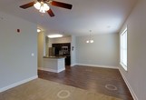 This single-floor space offers an open-concept design that seamlessly connects the kitchen, dining, and living areas. The kitchen is equipped with dark espresso cabinetry, stainless steel appliances including a refrigerator and microwave, and a peninsula with a built-in sink that doubles as a breakfast bar. Dark countertops complement the cabinetry, creating a cohesive, modern aesthetic.

Rich hardwood-style flooring extends throughout the main living areas, providing warmth and visual continuity. The neutral gray walls offer a versatile backdrop suited to a variety of décor styles. Overhead, the dining area is anchored by an elegant chandelier, while the living space features a ceiling fan, providing both light and air circulation.

The open layout allows for flexible furniture arrangements and a sense of spaciousness. Bright overhead lighting throughout ensures the space feels well-illuminated, and clean white baseboards and trim provide a crisp finish. Overall, the unit presents a contemporary, well-appointed interior designed for comfortable, everyday living.